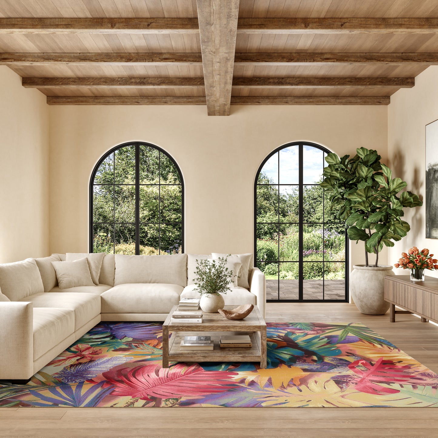 Neutral beige living room with a sectional sofa, colorful tropical rug, arched black-framed windows, wooden beam ceiling, and a potted plant.