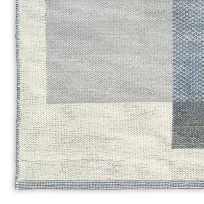 Neutral patchwork woven rug with cream, gray and pale blue blocks; soft textured, contemporary geometric design.