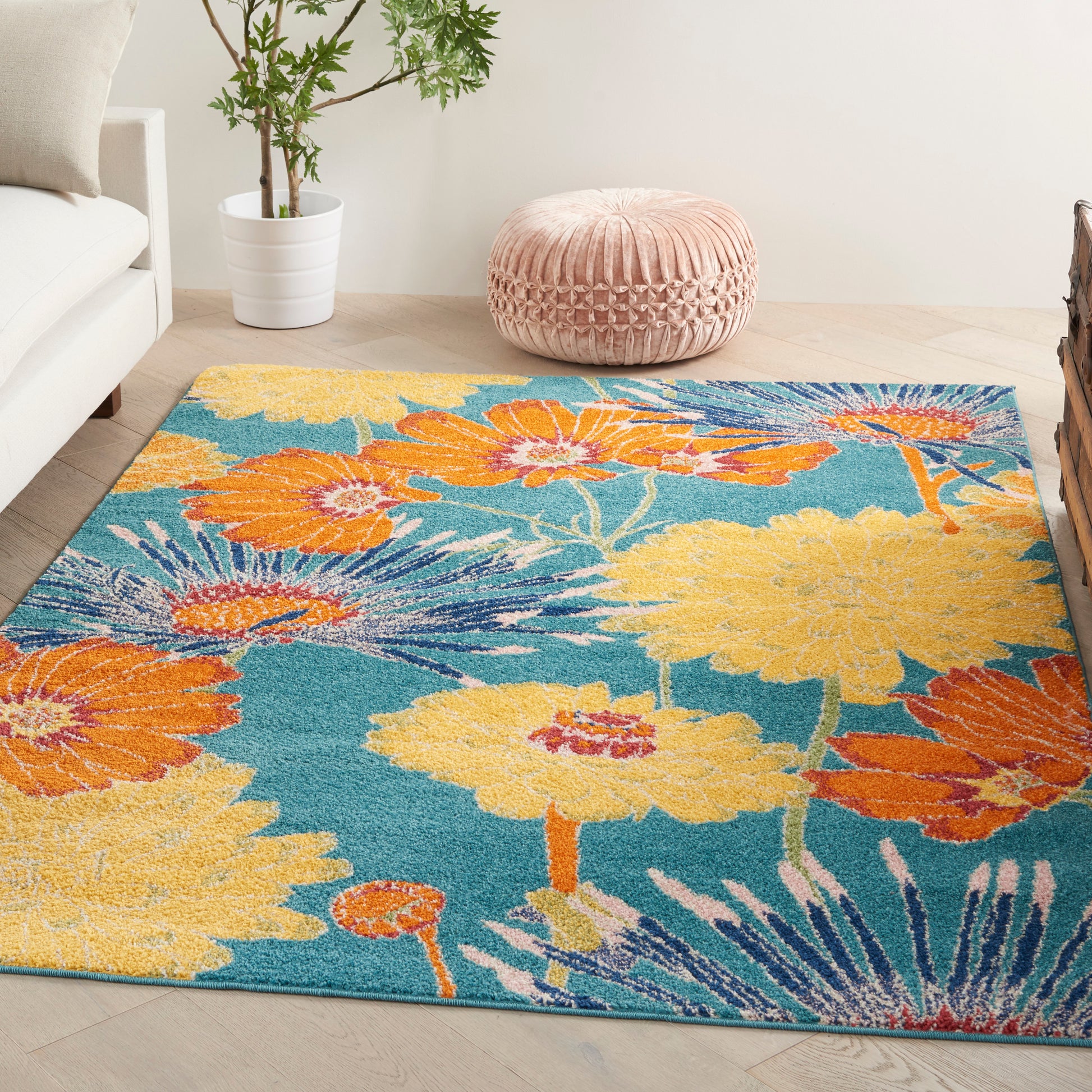 Vibrant floral area rug with teal background and orange-yellow blooms; woven texture in a modern living room.