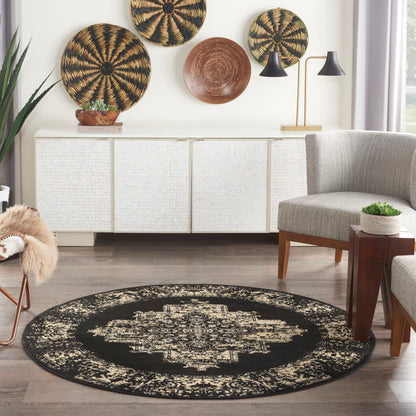 Round black and beige distressed patterned area rug on wood floor in boho chic living room.