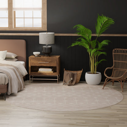 Cozy modern bedroom with beige upholstered bed, wooden nightstand, round beige rug, potted palm and wicker chair.
