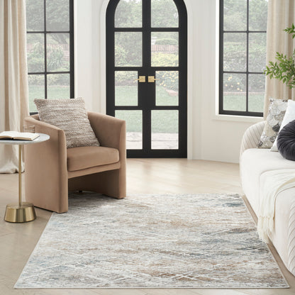 Tan armchair and cream sofa with gold side table, blue-gray abstract rug in a bright living room with arched black doors.