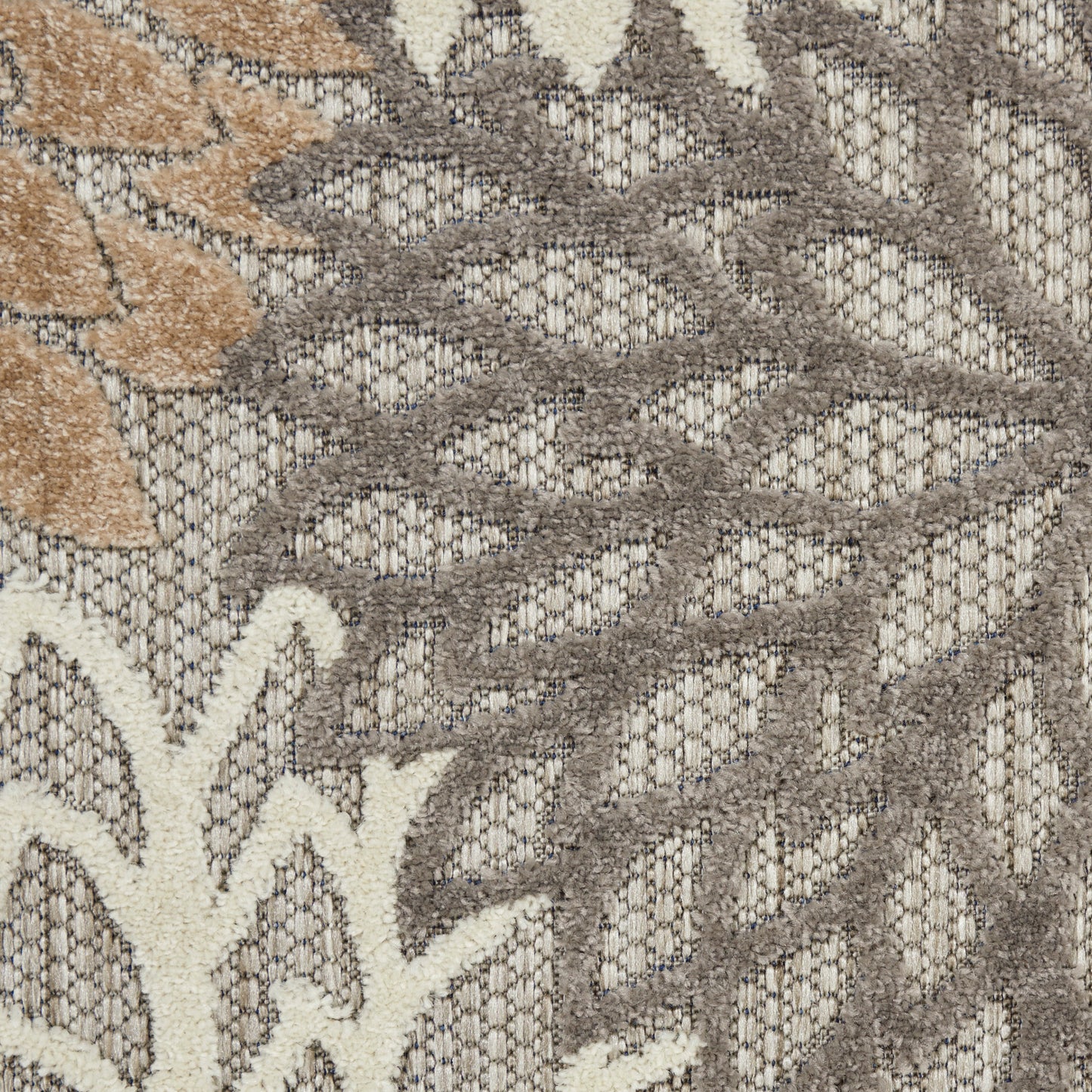 Beige & taupe outdoor rug with a subtle leaf floral motif in an open, textured weave.