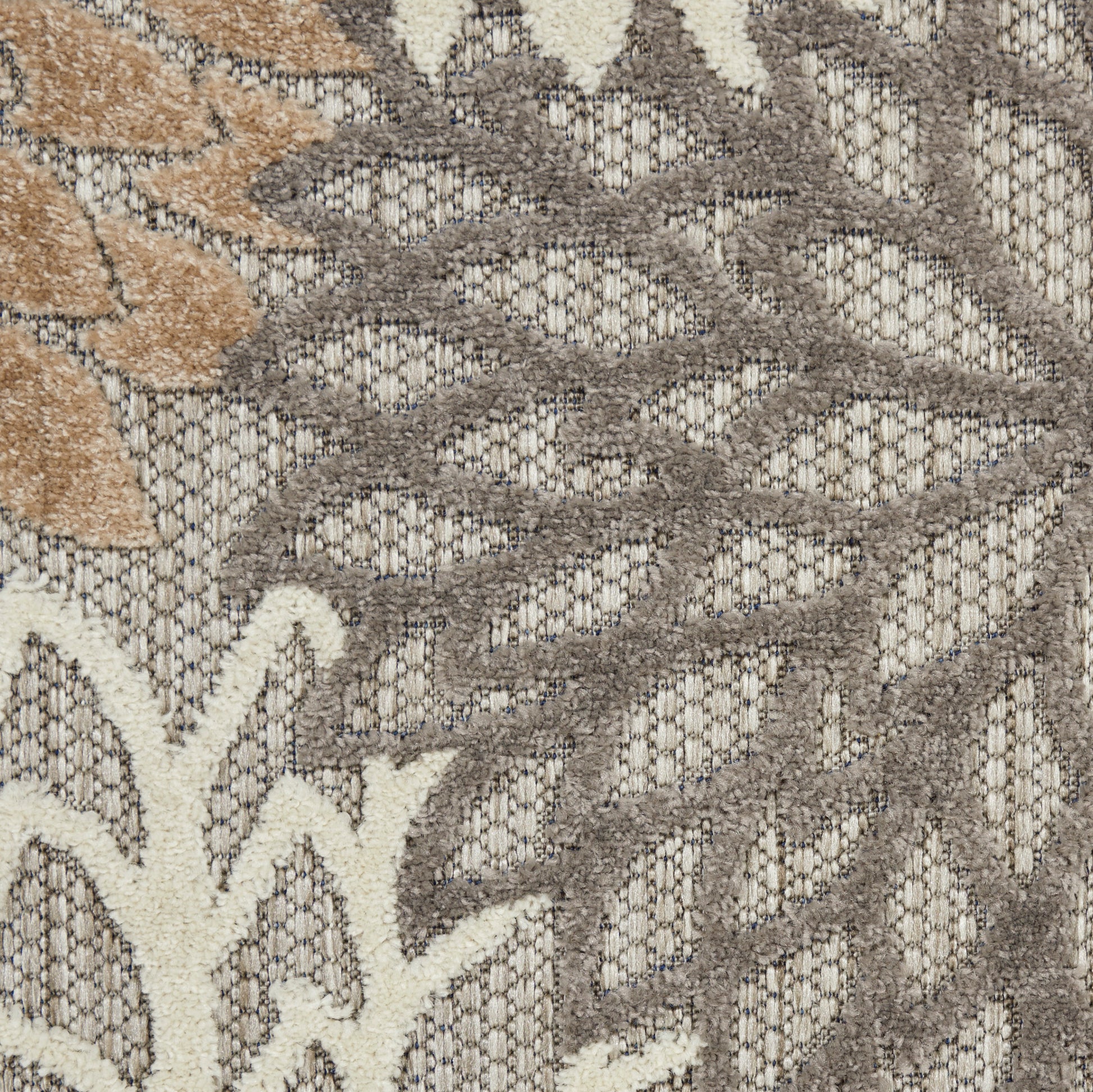 Beige & taupe outdoor rug with a subtle leaf floral motif in an open, textured weave.