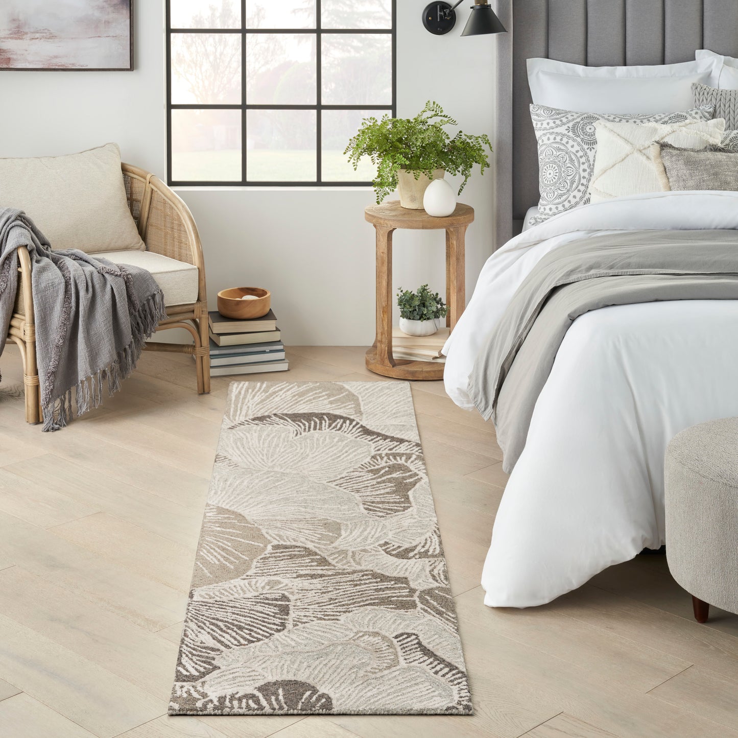 Beige palm-leaf flatweave rug runner in a cozy farmhouse bedroom with light wood floors and white bedding.