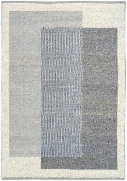 Modern geometric rug featuring overlapping gray and blue rectangles in cool tones with a cream border.