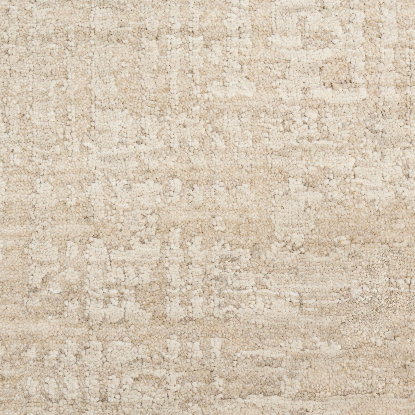 Beige textured area rug with soft cream-tan patches in an abstract, woven pattern.