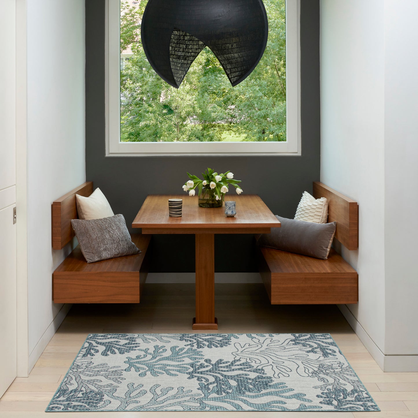 Blue botanical area rug on the floor in a room with a window.