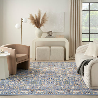 Neutral living room with blue patterned rug, beige sofa and armchair, cream console table, pampas grass vase, and window.