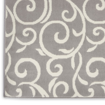 Close-up of gray rug with bold white swirling scroll pattern and visible woven texture.