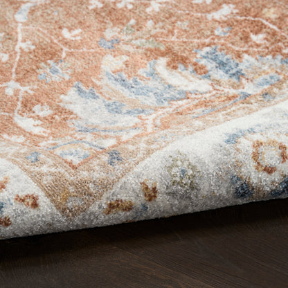 Soft oriental rug with peach, blue and ivory floral motifs, folded edge showing plush texture on dark wood floor