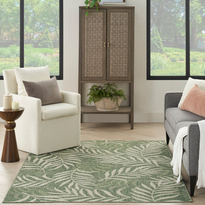 Cozy living room with a tall brown cabinet with woven doors, beige armchair, gray sofa, and a green fern outdoor rug.