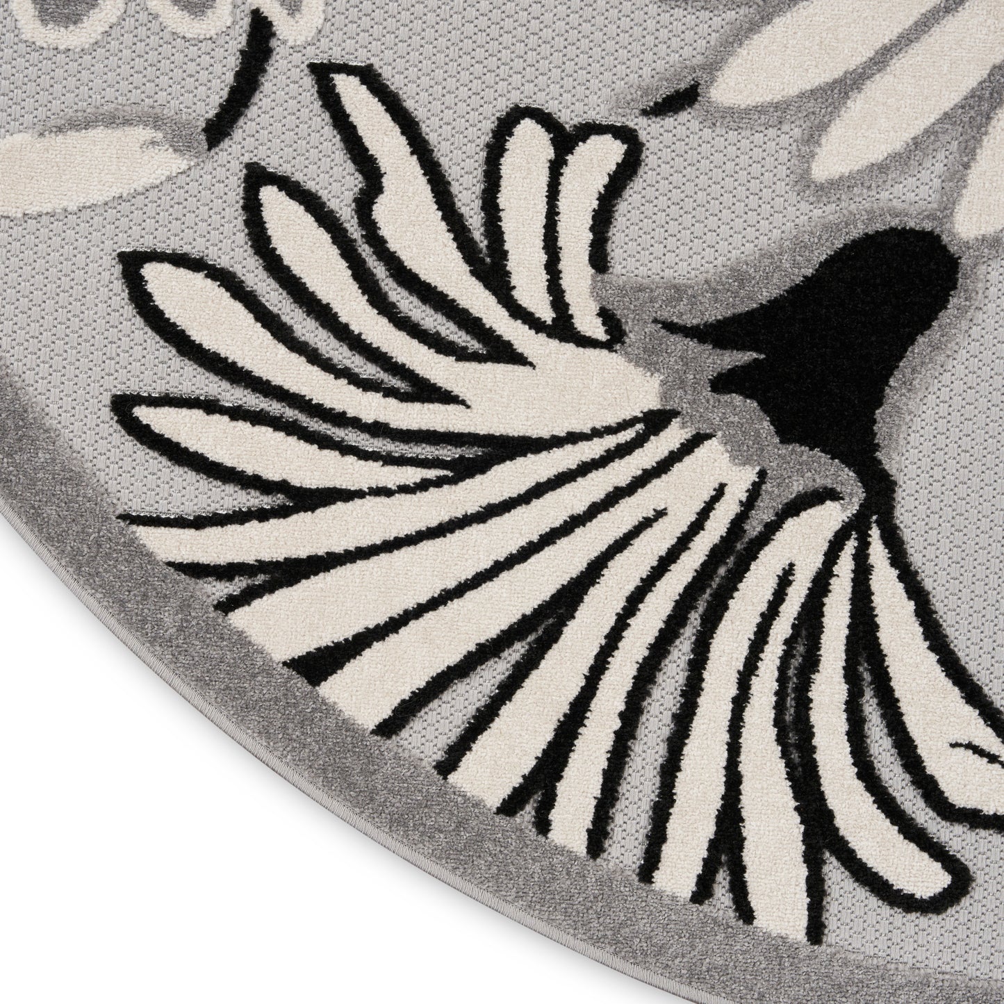 Round grey rug with cream and black floral petal motif and soft woven texture.
