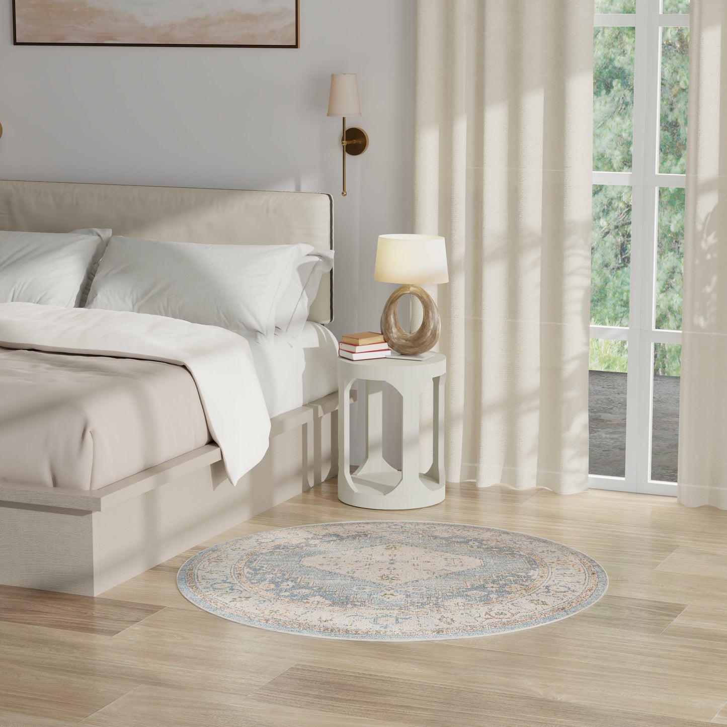 Neutral bedroom with white bedding, light wood floor, round blue-gray rug, white circular side table and lamp.