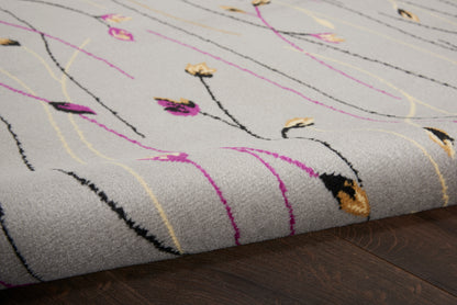 Grey looped-pile area rug with abstract pink, yellow and black lines on dark wood floor.