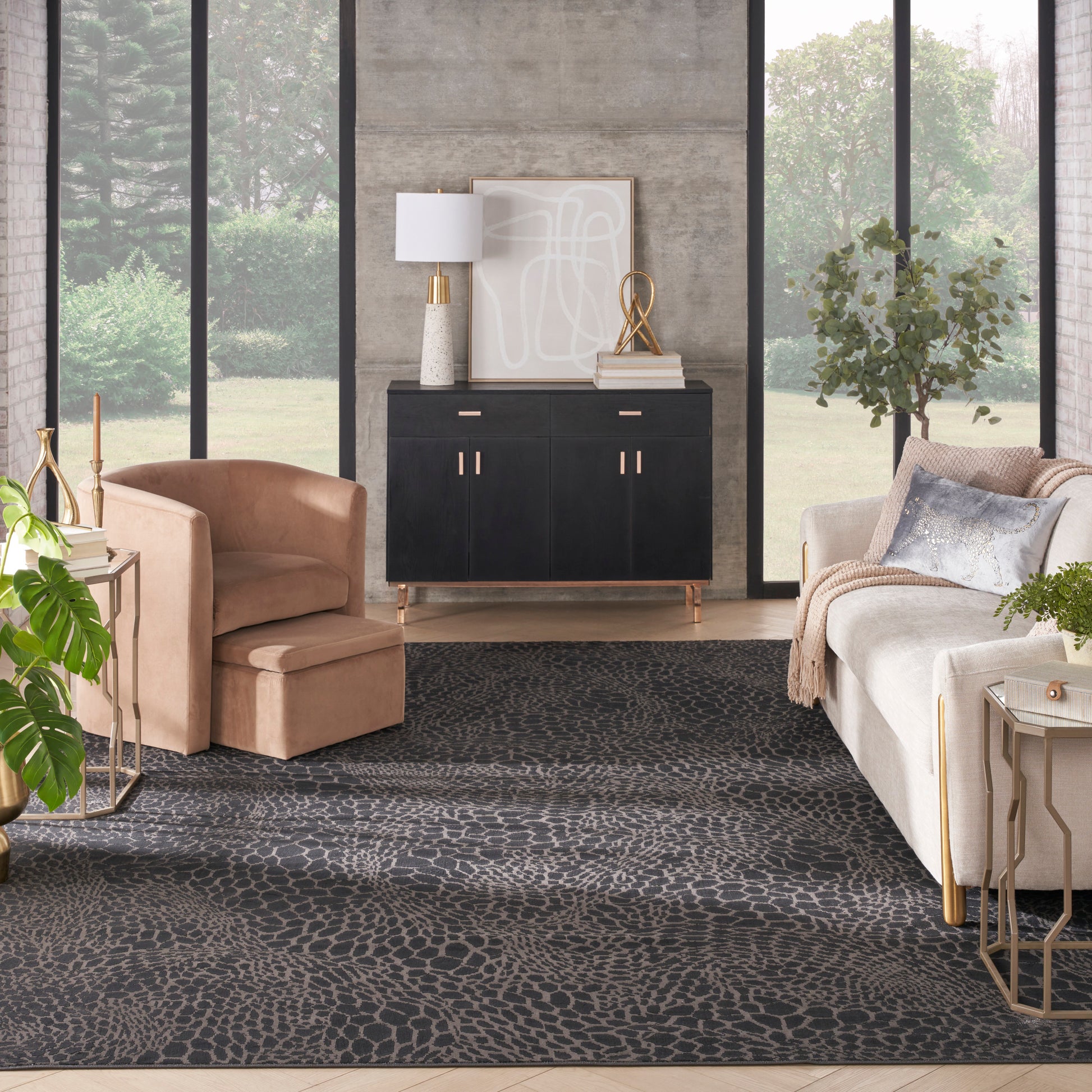 Elegant living room with black sideboard, beige lounge chair, cream sofa, dark patterned rug, gold accents, large windows.
