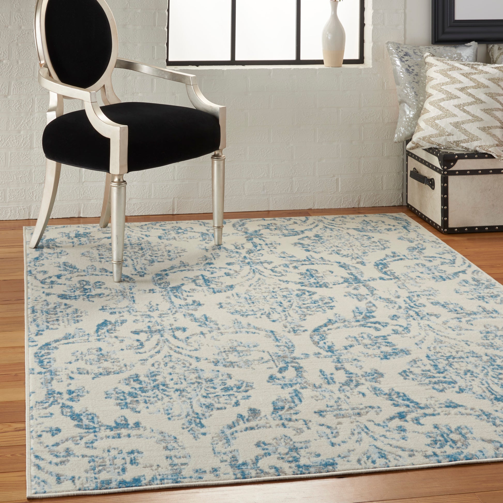 Cream finished wood-framed armchair with black upholstery on a blue-and-cream patterned area rug in a bright room.