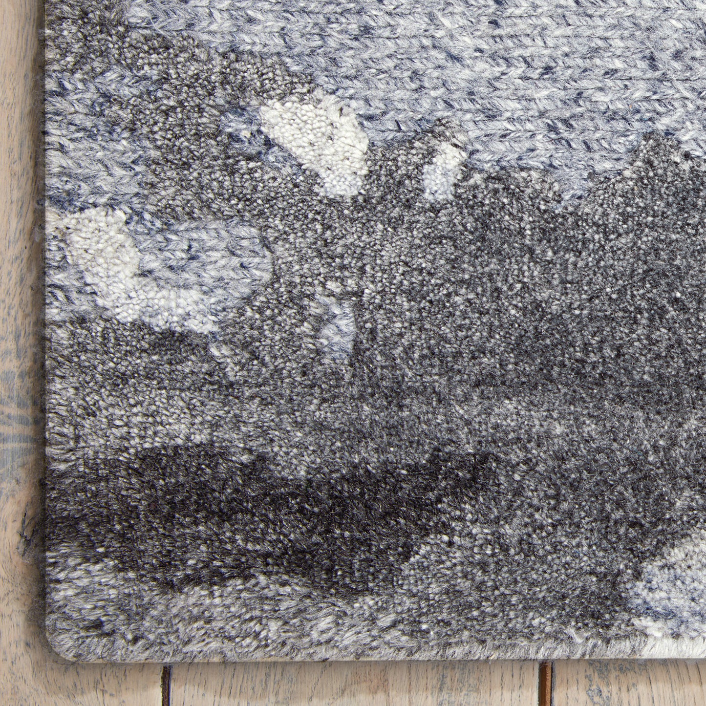 Blue-gray abstract patterned shag rug with thick plush pile, bound edges, laid on light wood floor.
