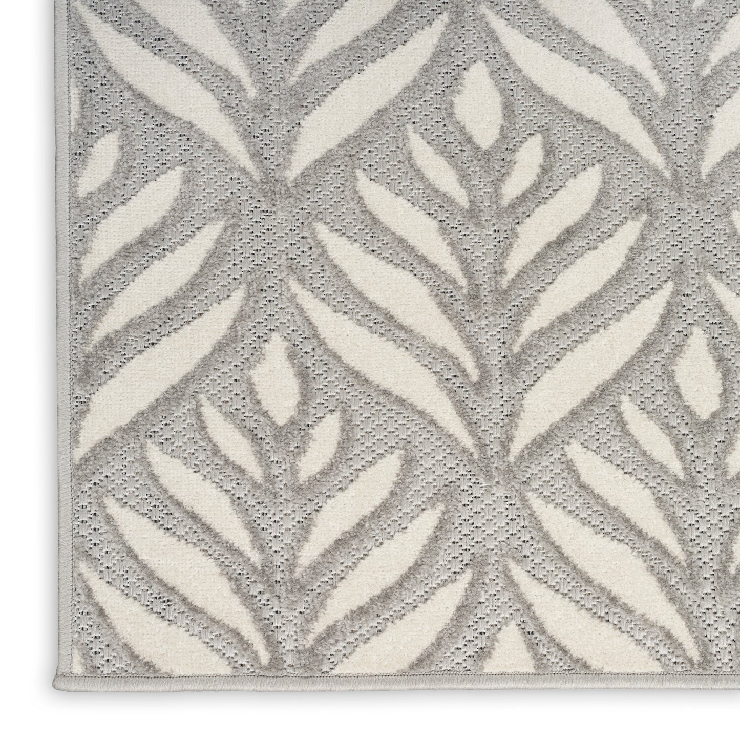 Grey textured rug with ivory leafy botanical pattern; loop-pile surface and pale border.