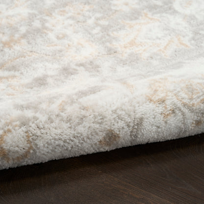 Close-up of a cream and beige shag rug edge with plush pile on dark wood floor.