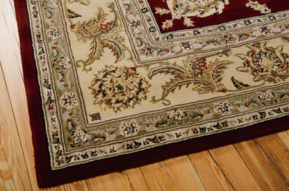 Cream oriental rug with burgundy border and intricate floral motifs on a warm wooden floor.