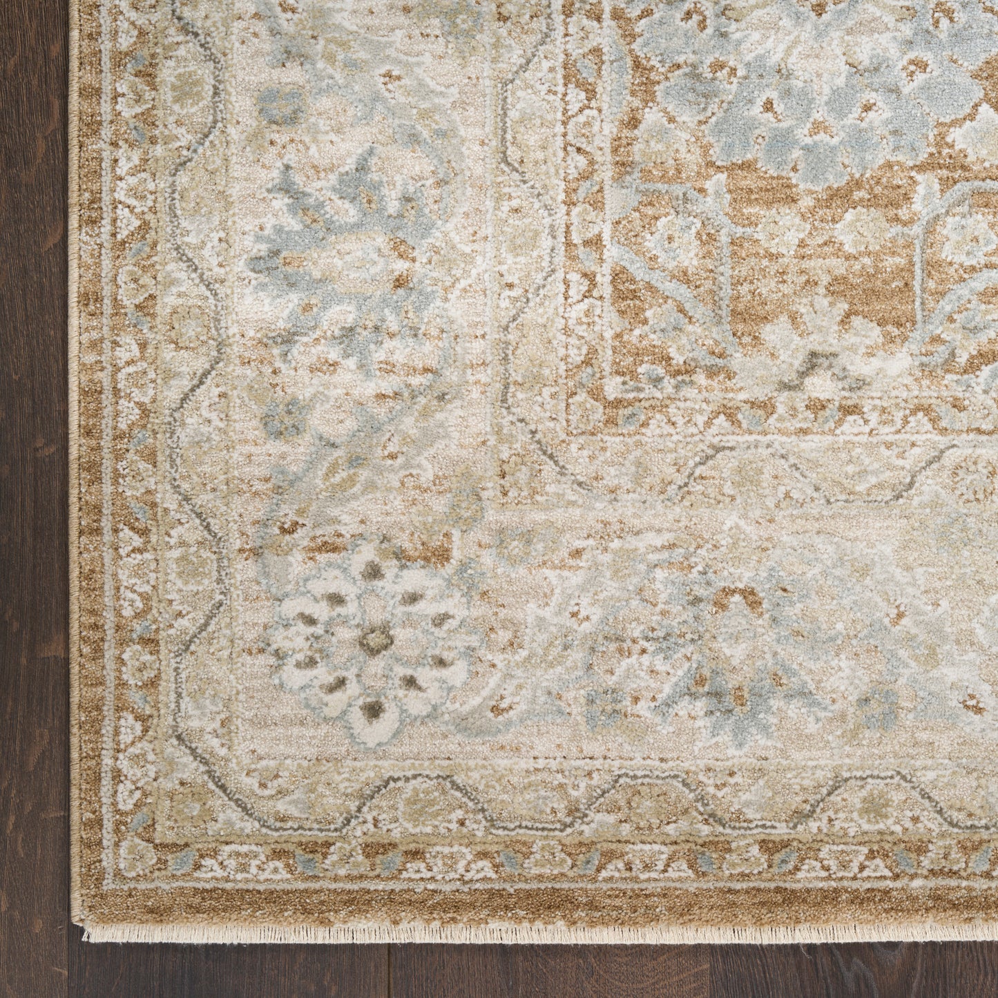 Beige and pale blue oriental area rug with floral motifs and ornate border on dark wood floor.