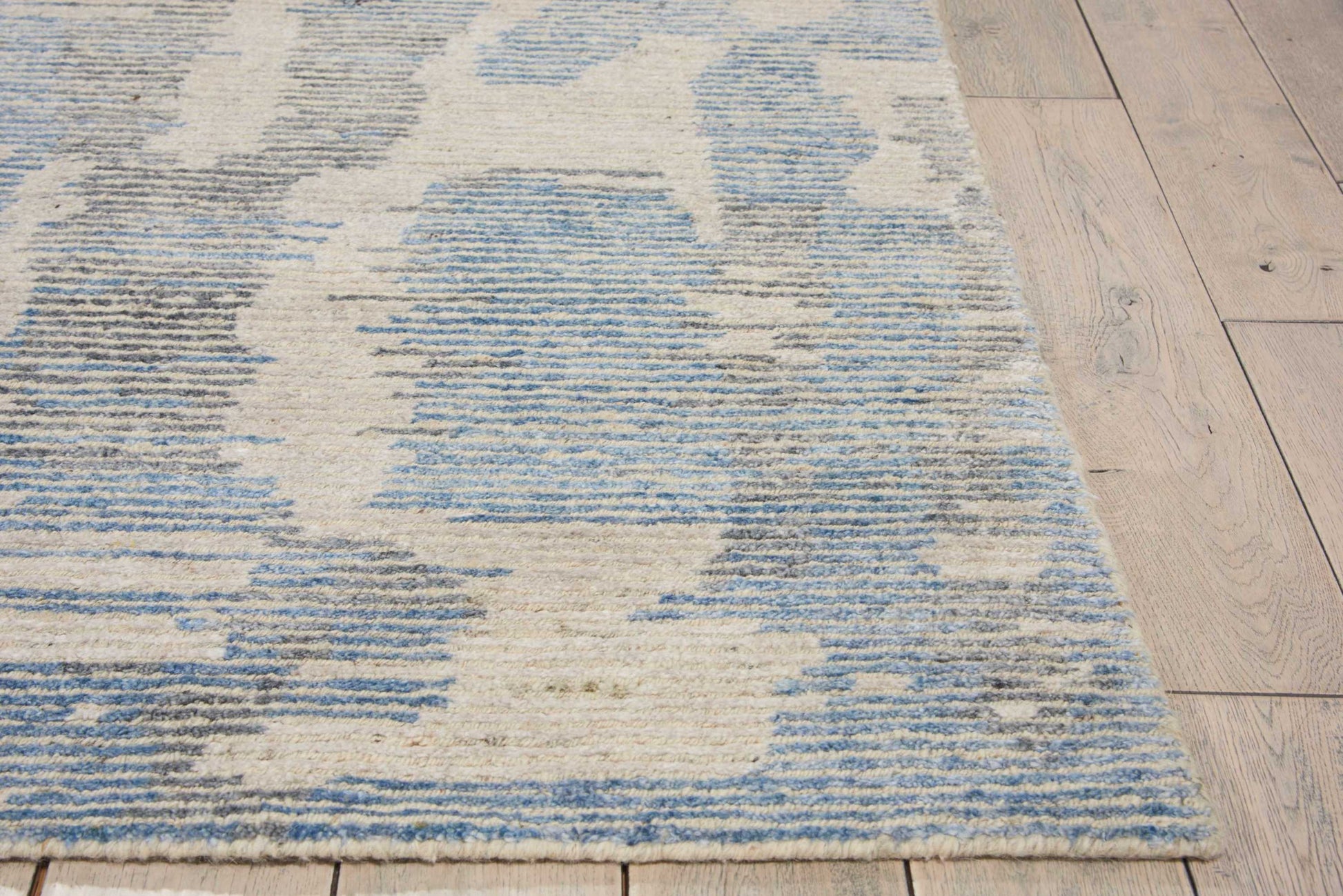 Blue and white abstract patterned area rug on light wood floor; soft, low-pile, modern geometric design.