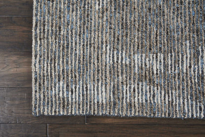 Rectangular shaggy loop-pile rug with blue, beige and gray vertical stripes on dark wood floor.
