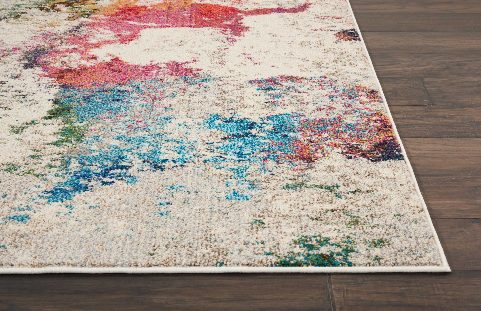 Cream abstract rug with vibrant multicolor splashes and white border on dark wood floor.
