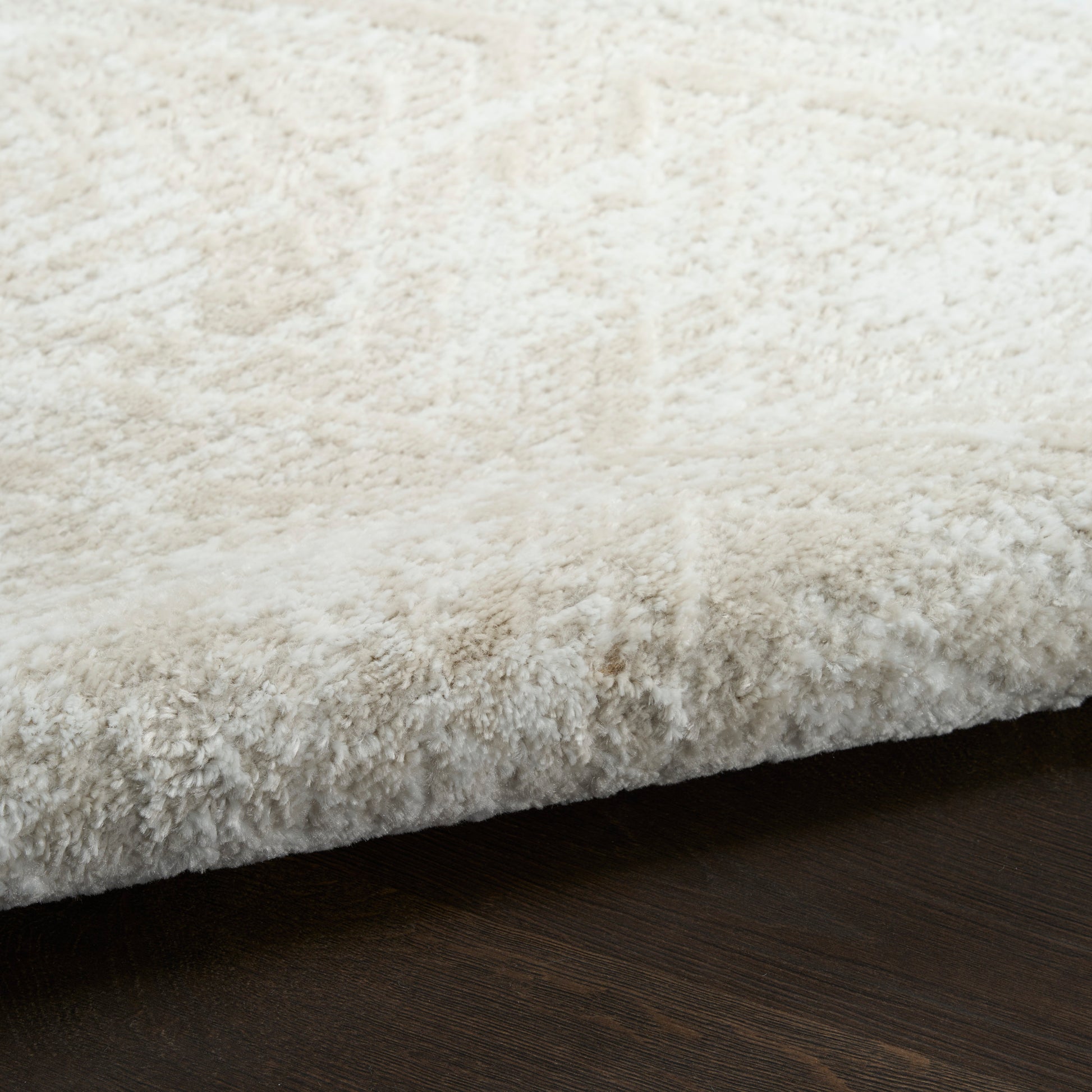 Ivory fluffy shag rug edge with plush pile on dark wood floor