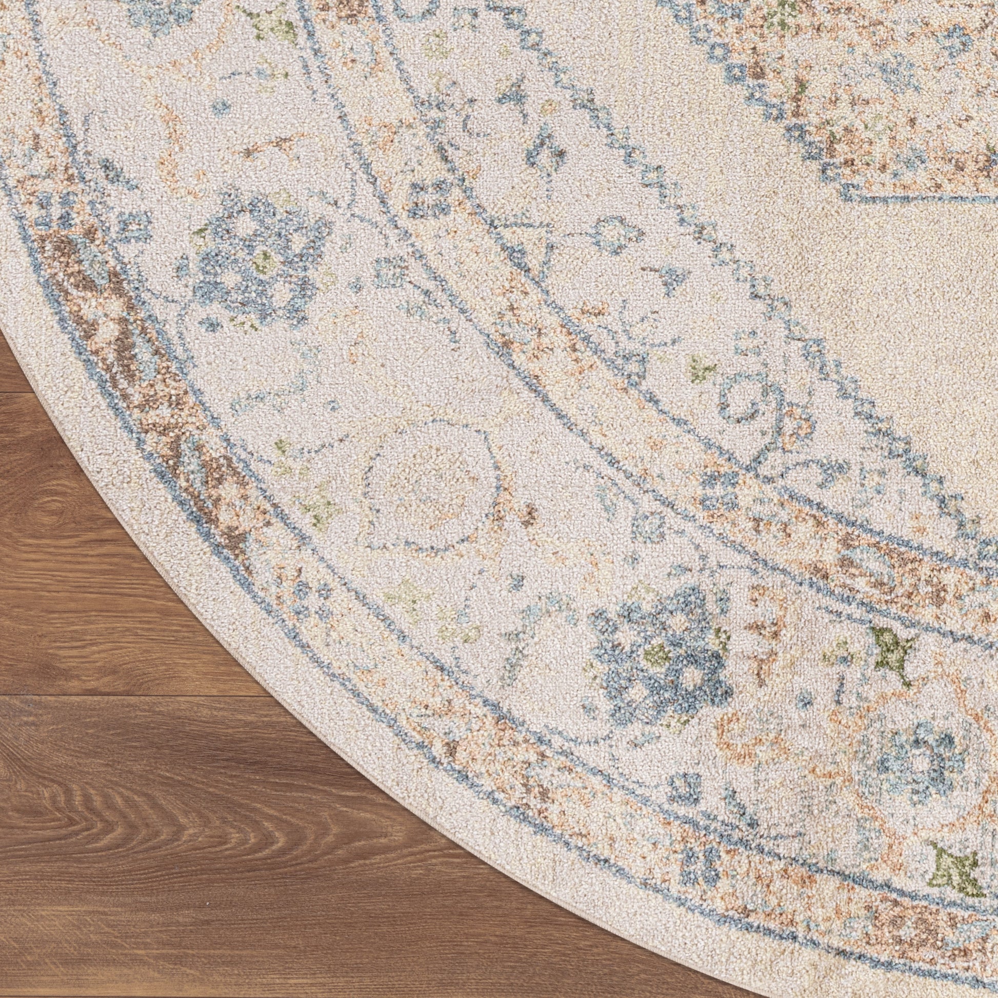 Round ivory rug with blue floral border and vintage medallion pattern on a wooden floor.