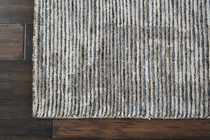 Light beige rug with dark blue vertical stripes on dark hardwood floor.