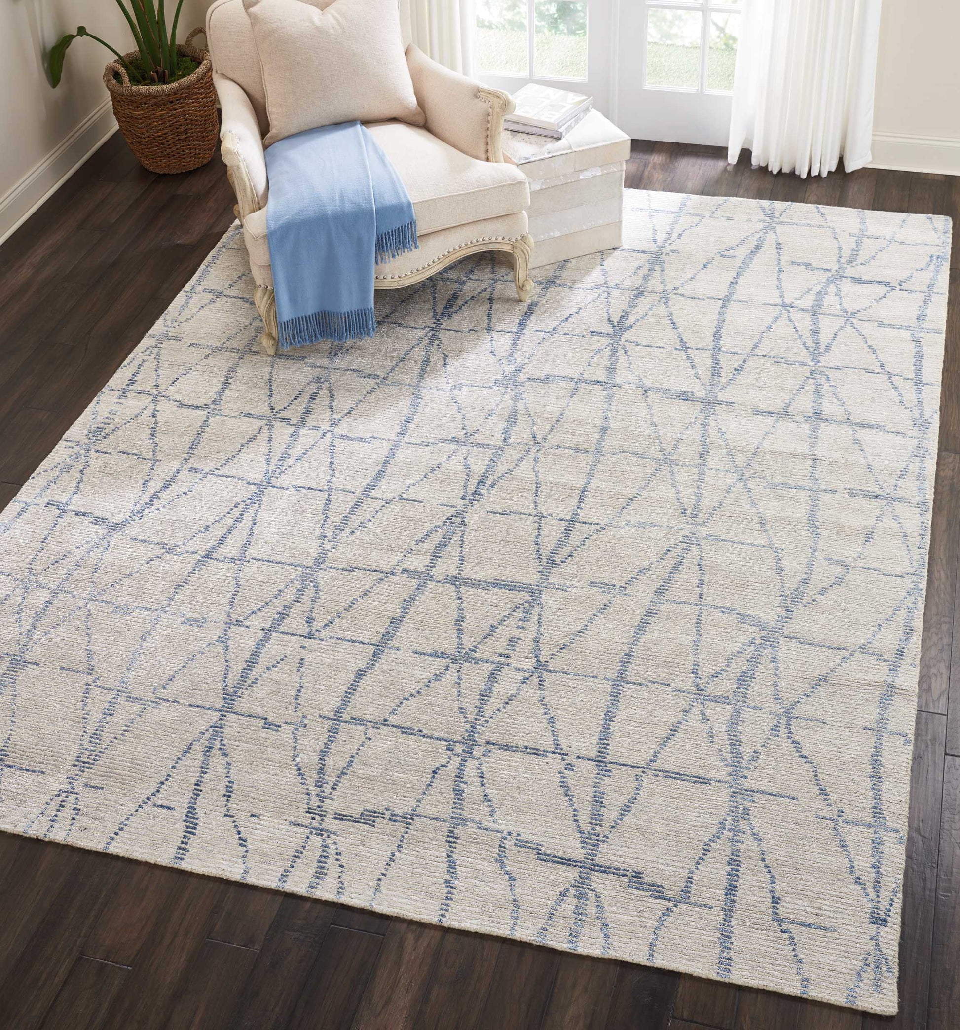 Cream rug with a light blue geometric lattice pattern in a living room beside a beige armchair and blue throw.