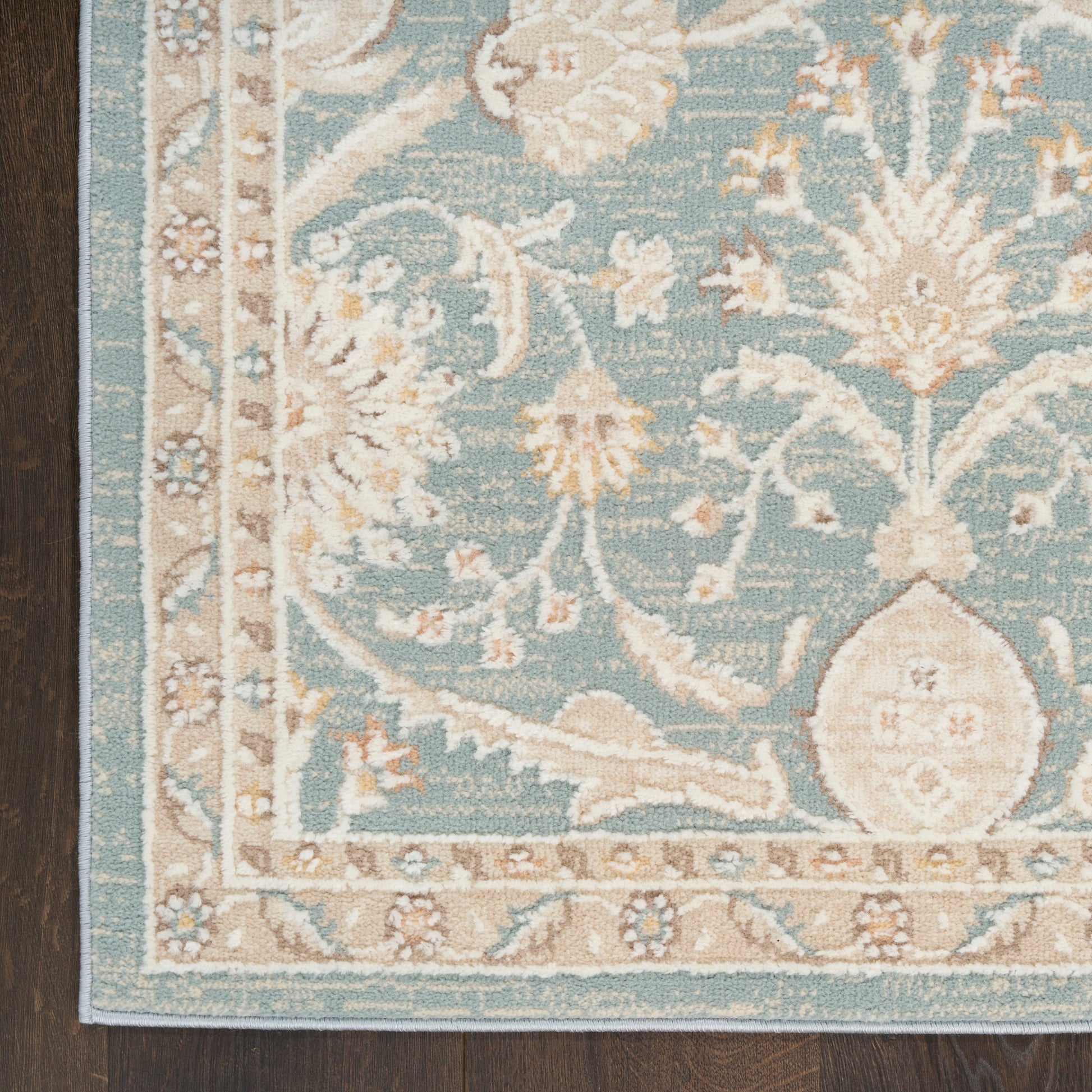 Teal oriental area rug with ivory floral motif & beige border on dark wood floor, vintage 5' x 7'.