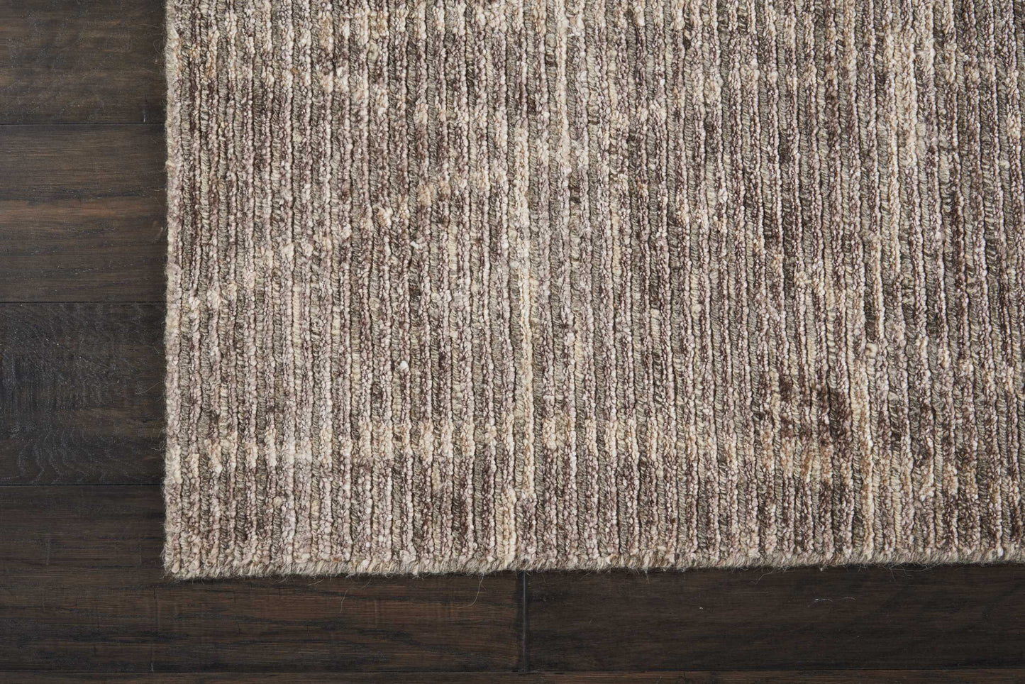 Beige-brown textured area rug with subtle vertical stripe pattern on dark wood floor.