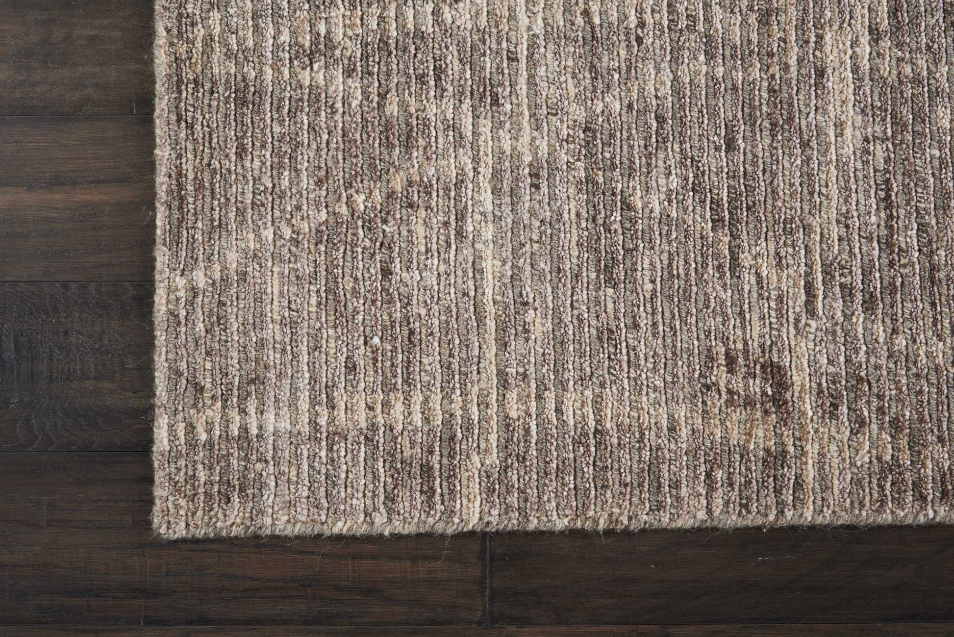 Beige-brown textured area rug with subtle vertical stripe pattern on dark wood floor.
