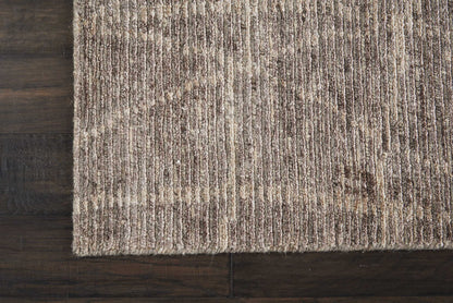 Beige-brown textured area rug with subtle vertical stripe pattern on dark wood floor.
