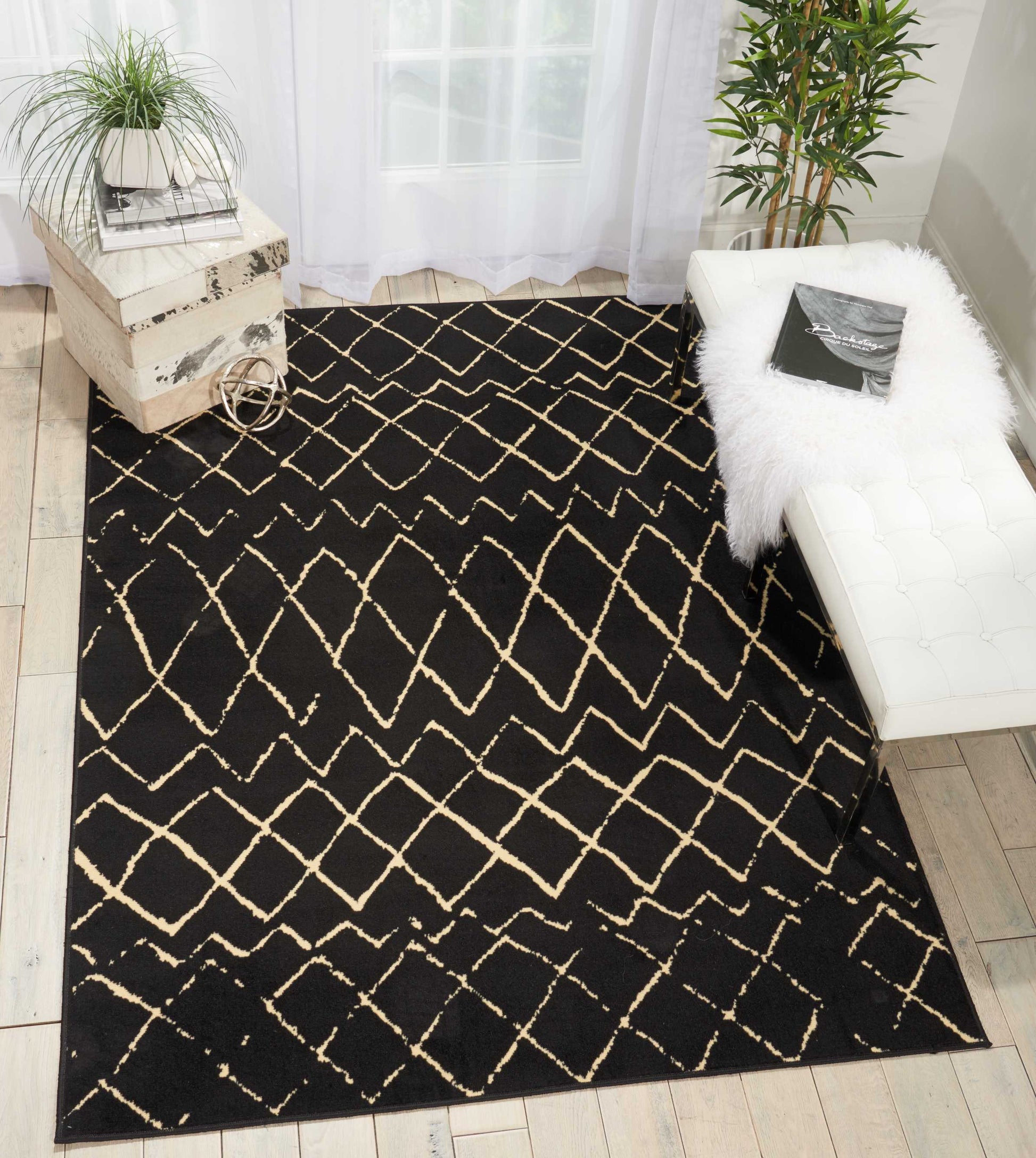 Black area rug with cream lattice pattern in a bright living room, paired with a white tufted bench and greenery.