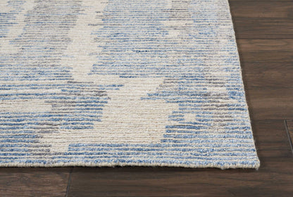 Blue and off-white abstract rug with a blocky geometric pattern on dark hardwood floor.