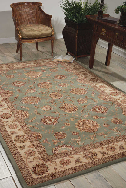 Rectangular teal oriental runner rug with beige border and floral pattern; wicker chair, wooden desk, and plants in a living room.
