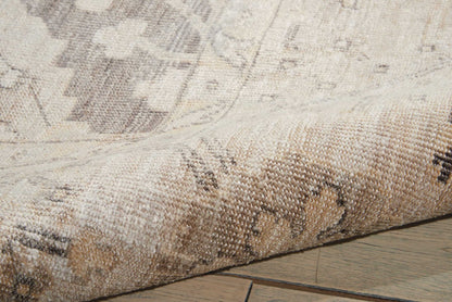 Beige and taupe woven rug with subtle geometric pattern, partially rolled on a wooden floor.