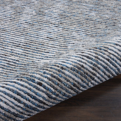 Blue and ivory striped textured rug with ribbed pile on dark wood floor.