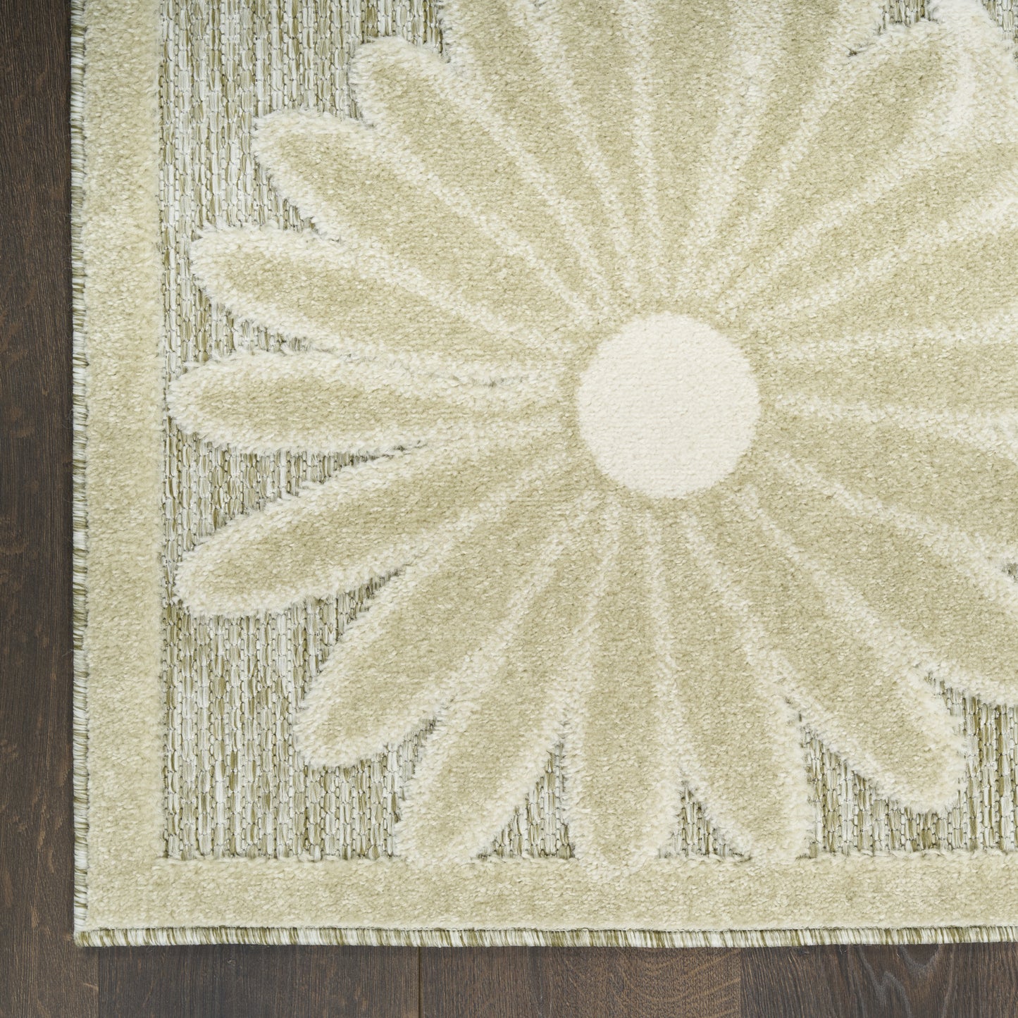 Cream outdoor rug with a large daisy center and striped textured border, on dark wood floor.