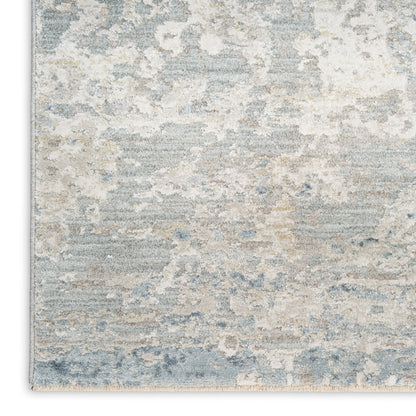 Abstract blue, gray, and beige area rug with distressed pattern and plush pile.