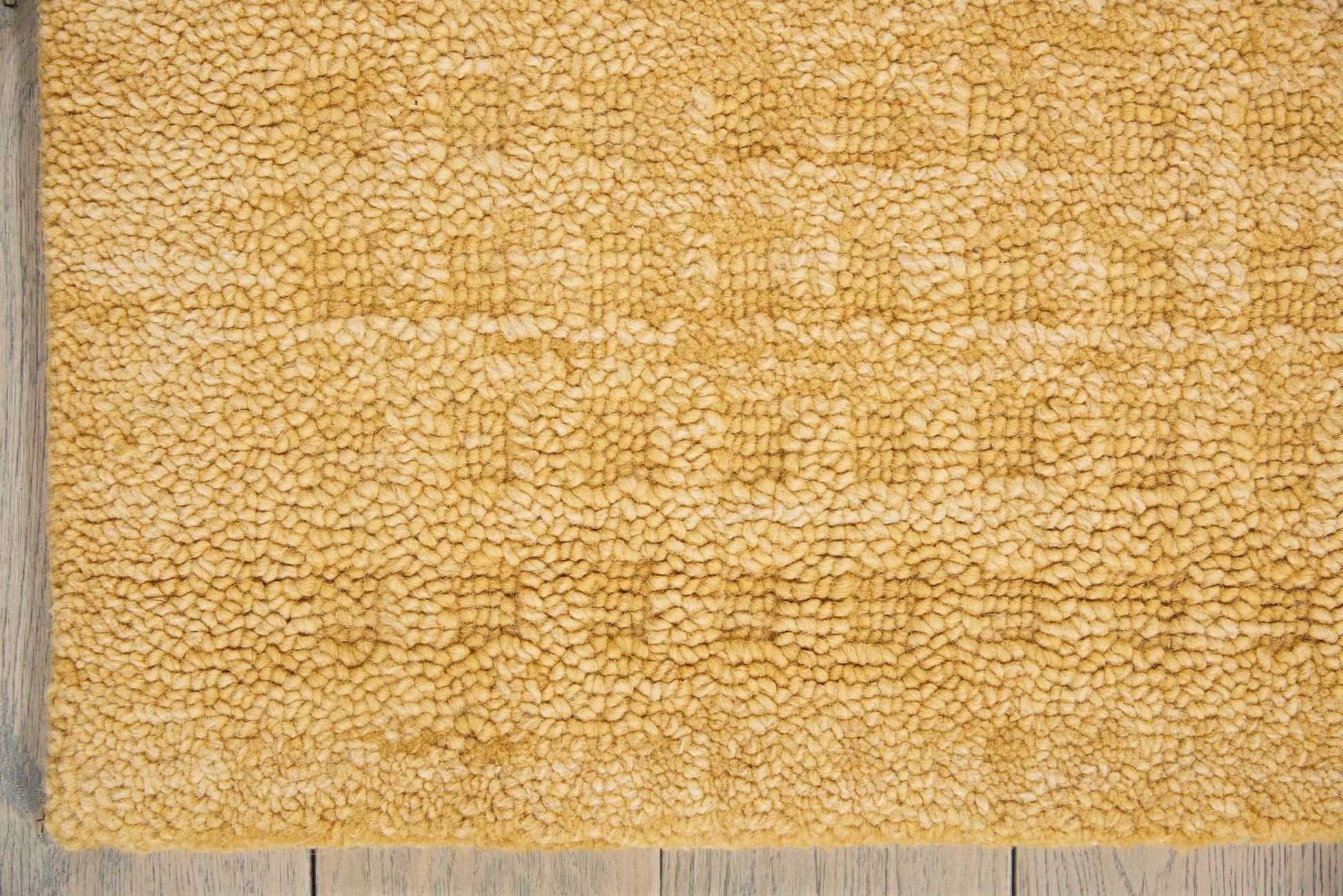 Tan plush shag rug on wooden floor; rectangular bath mat with soft, textured pile.