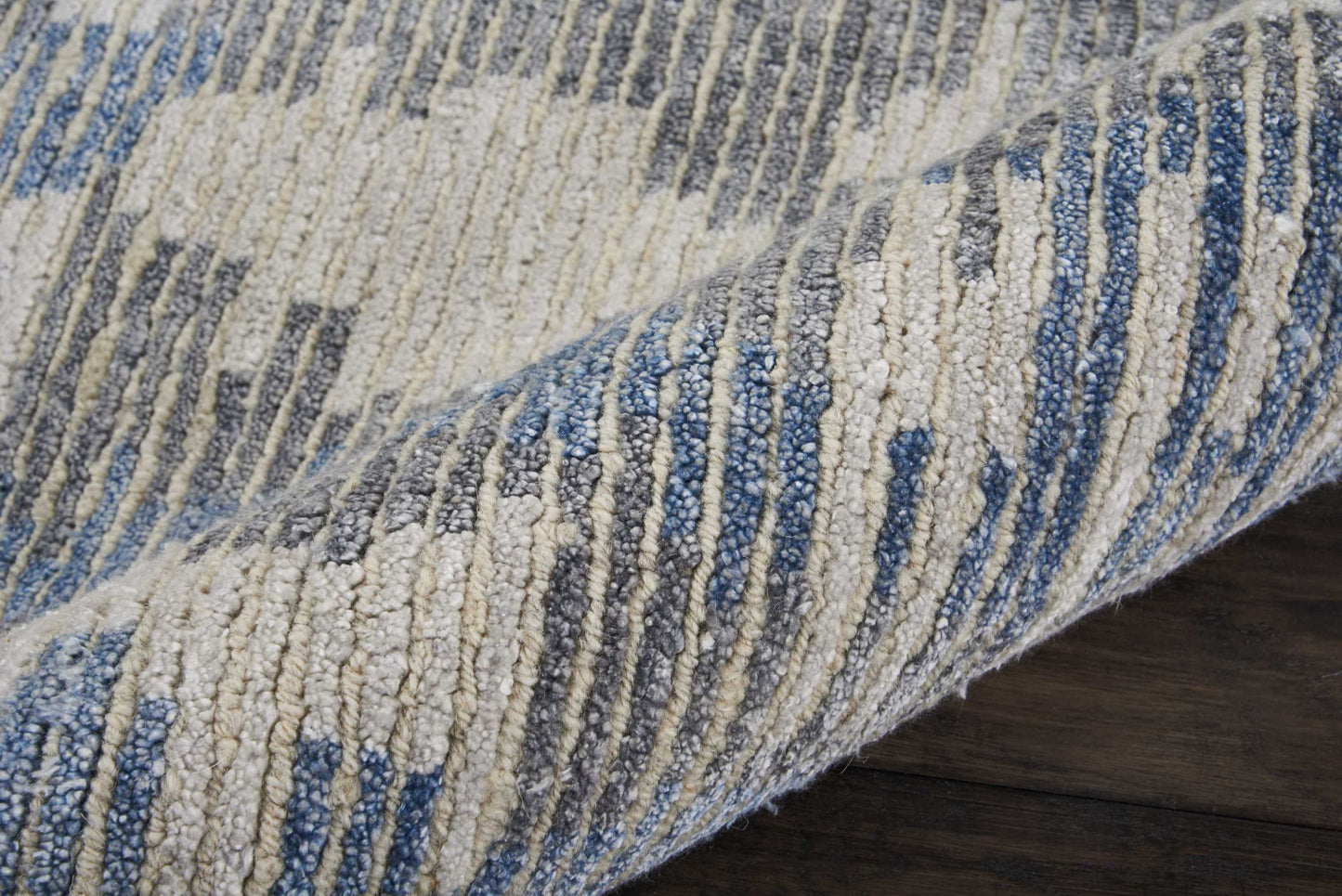 Blue & cream striped textured looped-pile rug on dark wood floor.