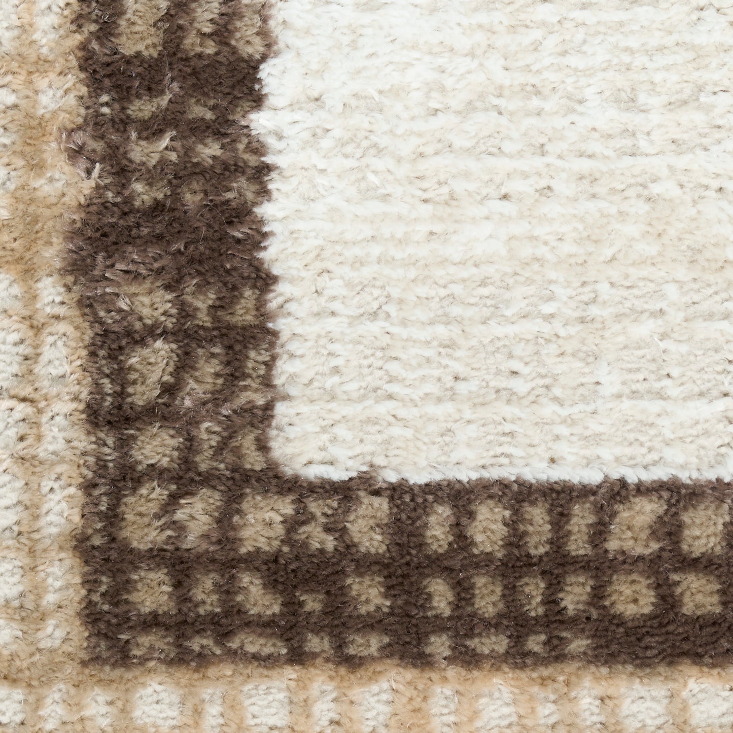 Cream and tan shag area rug with a dark brown border; plush, textured pile.
