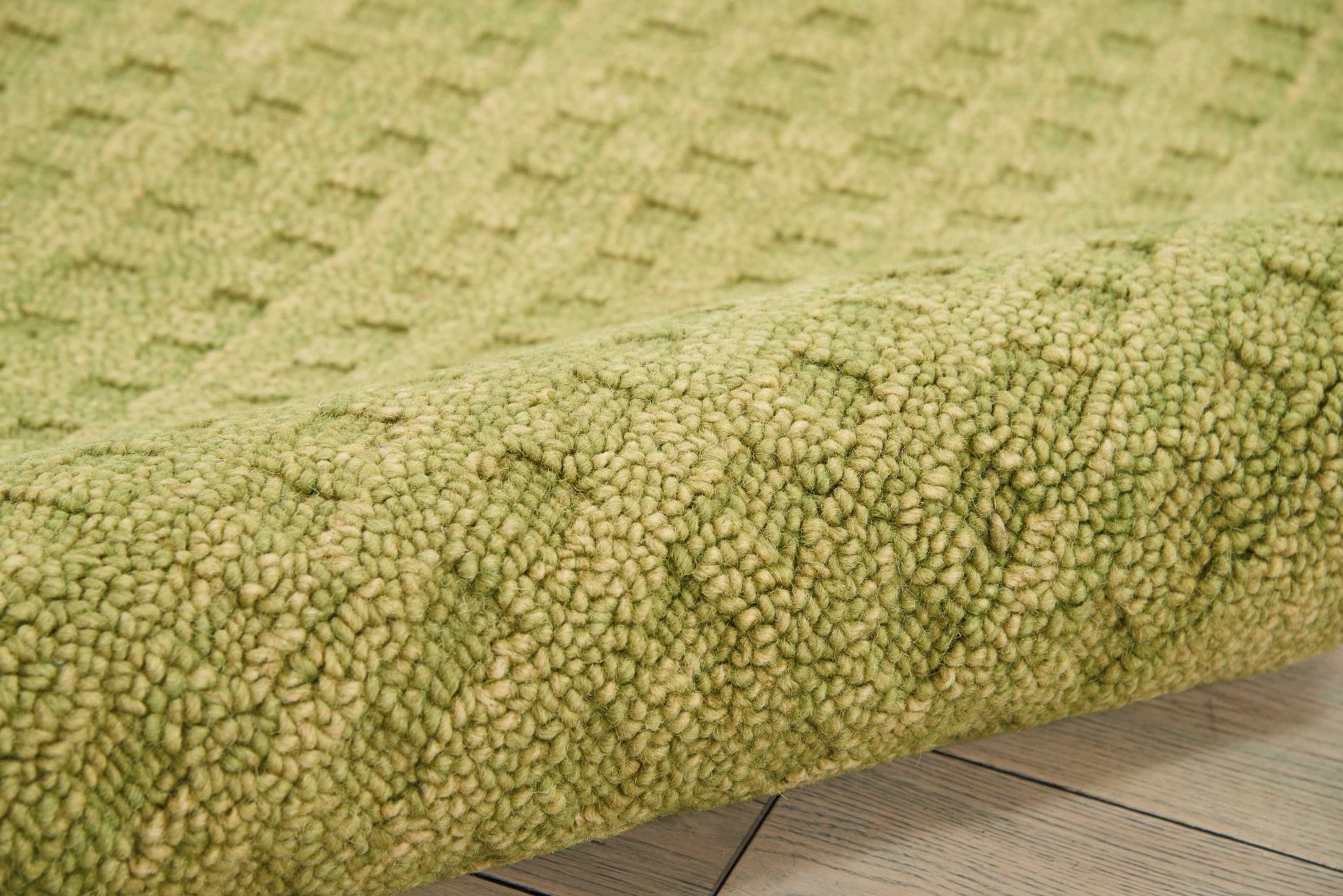 Olive green shag rug with dense looped pile resting on light wooden floor.