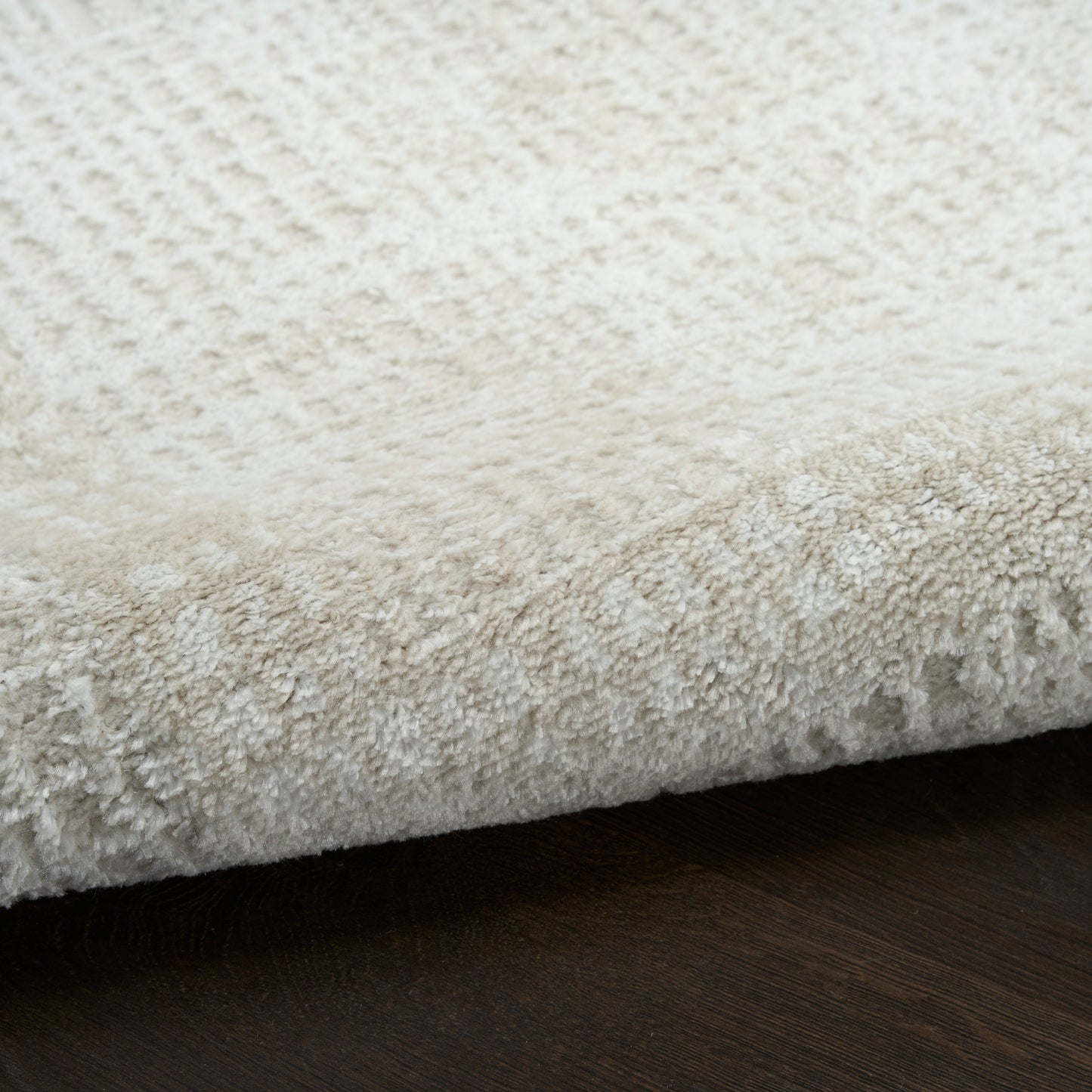 Cream shag rug with dense plush pile on dark wood floor; soft, cozy, modern style.