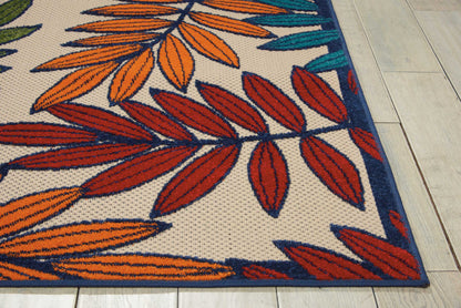 Leaf-pattern rug featuring orange, red, & teal leaves on a beige background with a dark blue border, on a light wooden floor.